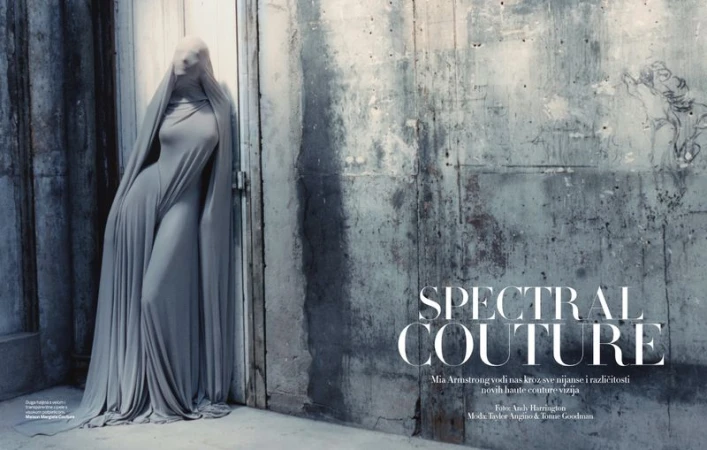 Fashion shot of a person draped in a grey, flowing dress standing against a textured wall, creating a ghostly, spectral aesthetic.
