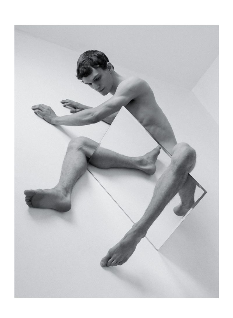 Black and white art photo of a fair-skinned young man posing with mirrors, creating a visually striking and geometrically-enhanced composition.
