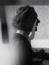 Grainy monochrome profile silhouette of a smiling woman with a fluttering neck scarf for Silhouette Magazine.