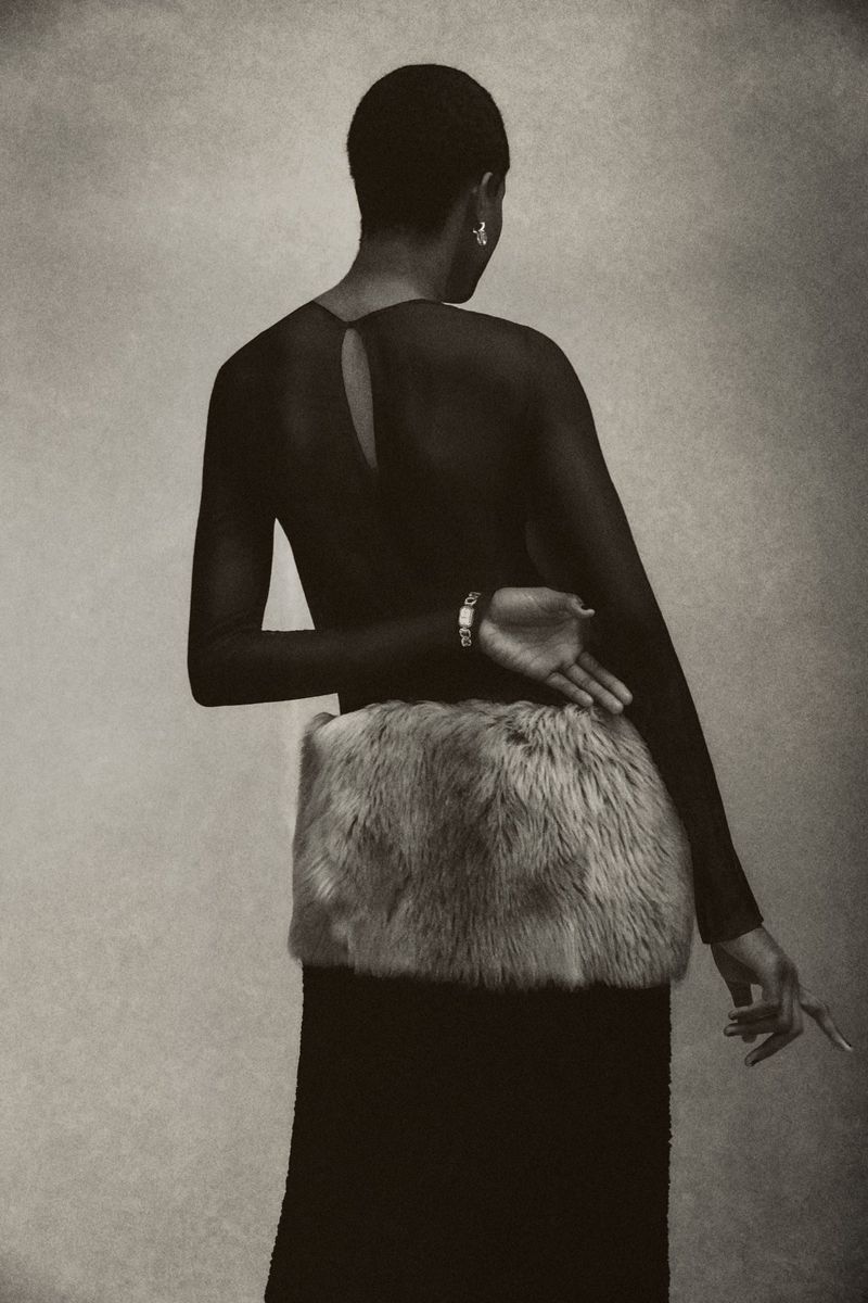Adult female model posing in a black dress with a faux fur muff. Shot in a photo studio with neutral background and fine art style.