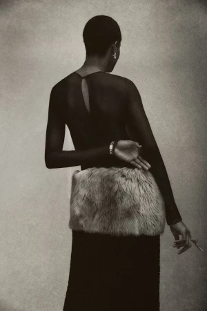 Adult female model posing in a black dress with a faux fur muff. Shot in a photo studio with neutral background and fine art style.