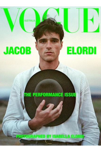 Vogue Australia cover featuring Jacob Elordi wearing a white shirt and holding a black hat against a soft, blurry outdoor background.