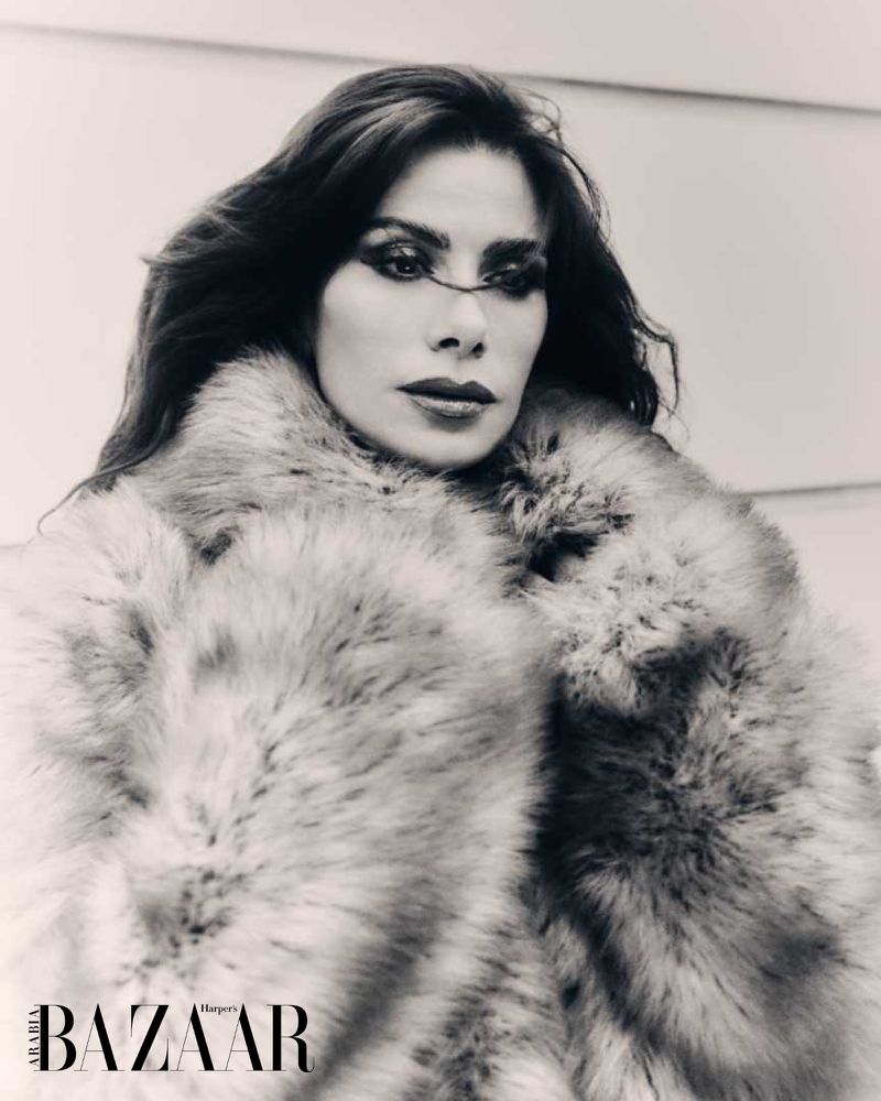 Monochrome fashion portrait of a woman with dark hair, wearing a fur coat, and featuring 'Harper's Bazaar' magazine branding.