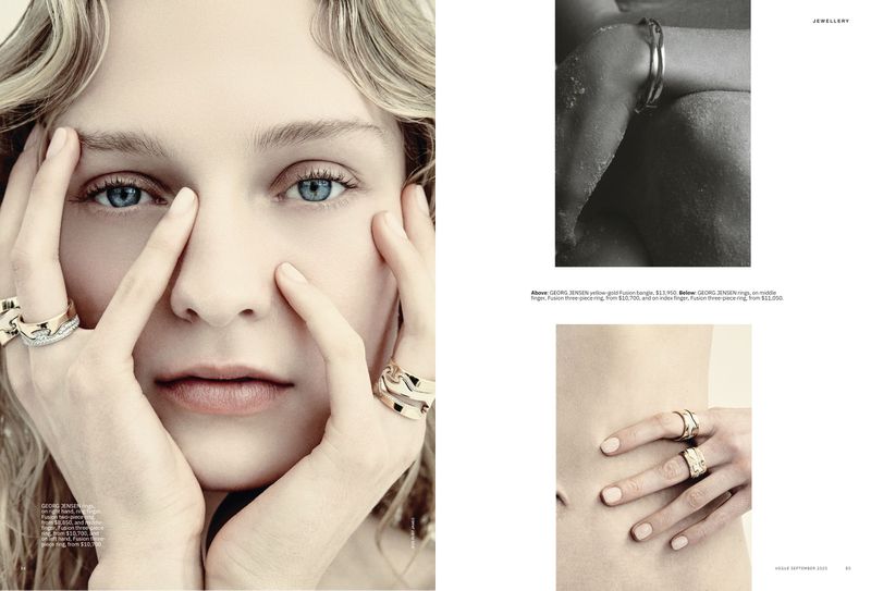 Close-up of a blonde woman with blue eyes, fair skin, and light pink lips wearing gold rings, set in a beauty or fashion editorial.