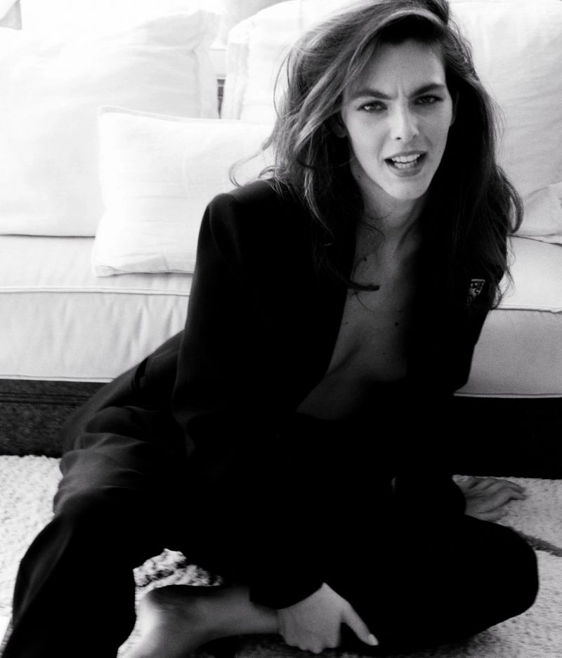 Model Vittoria Ceretti seated on a carpet in front of a white sofa wearing a black blazer for D Repubblica Sostiene Vittoria