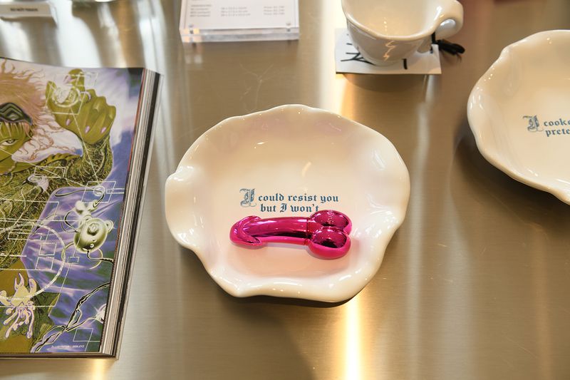 Novelty item on a plate with text that reads 'I could resist you but I won't'. Pink phallic object sits in the middle of the plate.