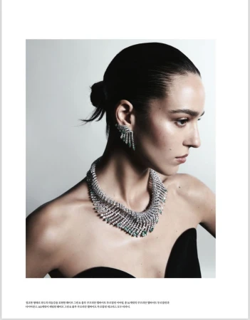 Close-up of an adult woman wearing a silver-and-green statement necklace and matching earrings in a studio environment.