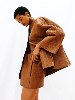 Model wearing a structured brown textured jacket and matching shorts against a plain white background