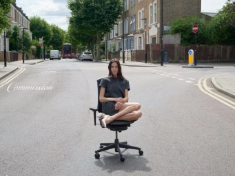 Alexa Chung seated on an office chair in the middle of a residential London street for Commission F/W 25 Campaign