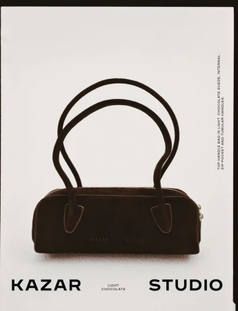 Dark brown Kazar brand top handle bag on a white background, featuring two tubular handles and minimal design, ideal for fashion.