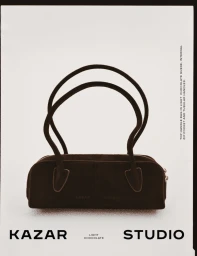 Kazar Studio light chocolate brown suede top handle handbag with tall tubular straps on an off-white seamless background.