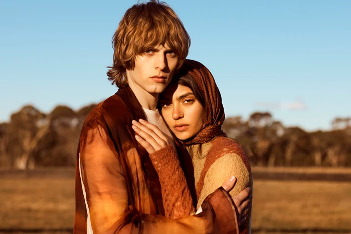 Two models embracing outdoors under a clear sky during sunset, shot by Milos Mlynarik for the Redleaf project by Base cast.