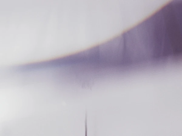 Abstract image with a soft, out-of-focus purple curve against a hazy white background, creating a dreamy, minimalist aesthetic.
