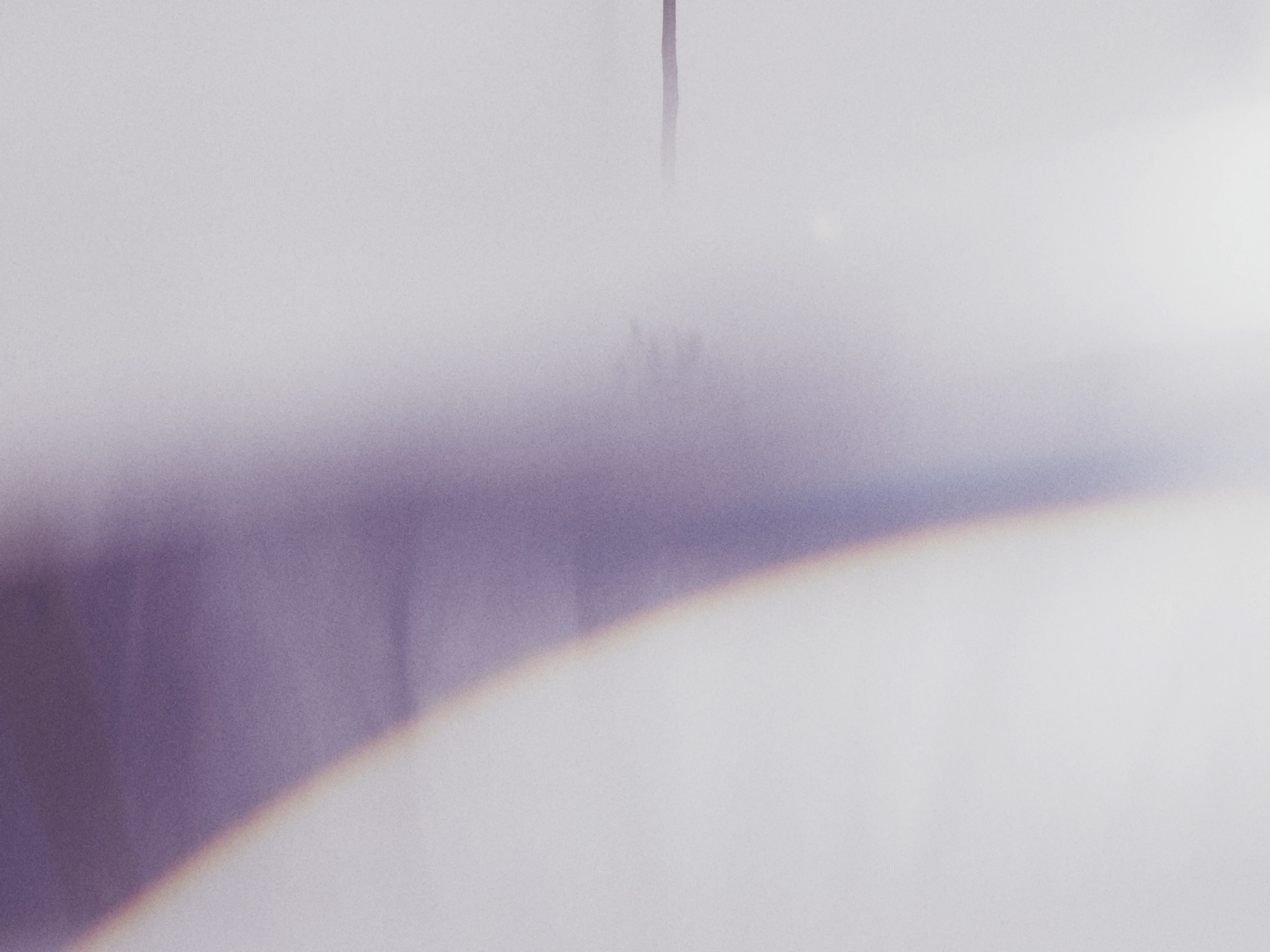 Abstract view of a blurred surface with a smooth gradient from white to light purple and an out-of-focus dark vertical line.