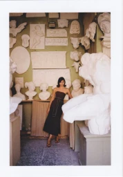 Woman in dark strapless dress posing among white plaster sculptures and reliefs in Luisa Pagani FW 25/26 Anielka campaign