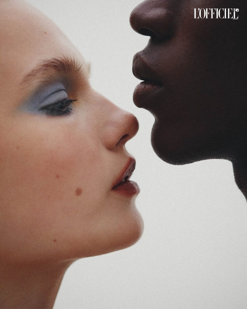 Close-up studio portrait of two diverse women with makeup. One model has dark skin and one has light skin against a neutral backdrop.