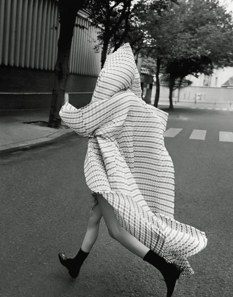 Person walking across a street wearing a striped dress and black shoes in a black and white editorial fashion shot.