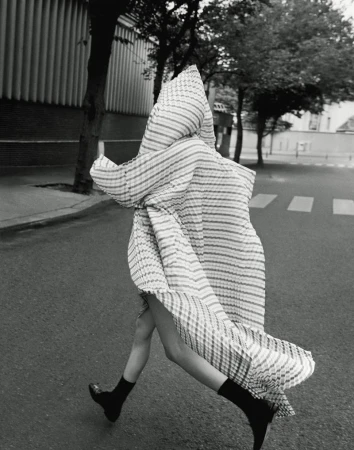 Person walking across a street wearing a striped dress and black shoes in a black and white editorial fashion shot.