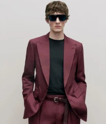 Model Nicolo Sala wearing dark sunglasses and a tailored burgundy suit over a black t-shirt against a neutral backdrop.
