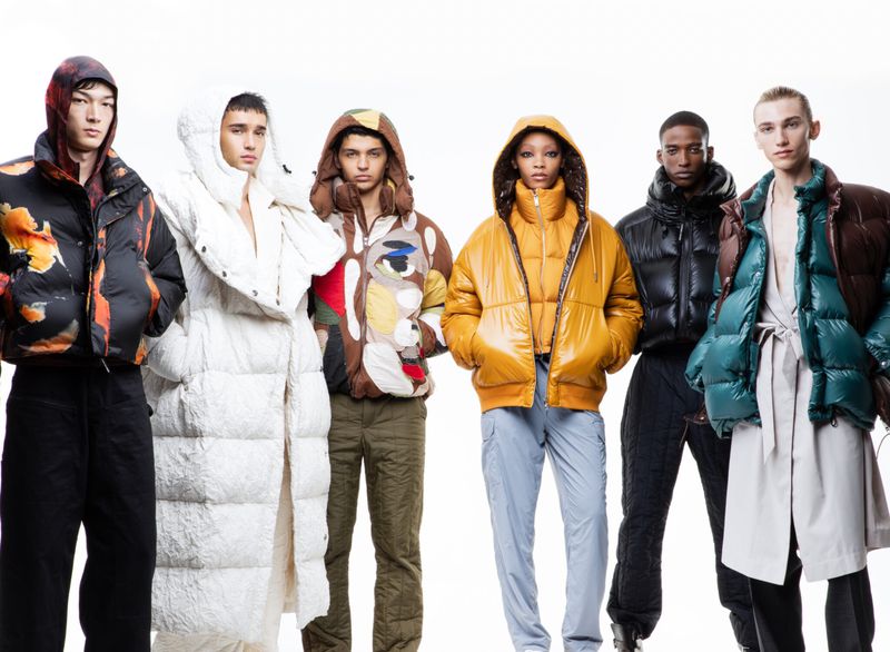 Group of six fashion models wearing colourful puffer jackets in a studio setting for a fashion editorial or advertisement.