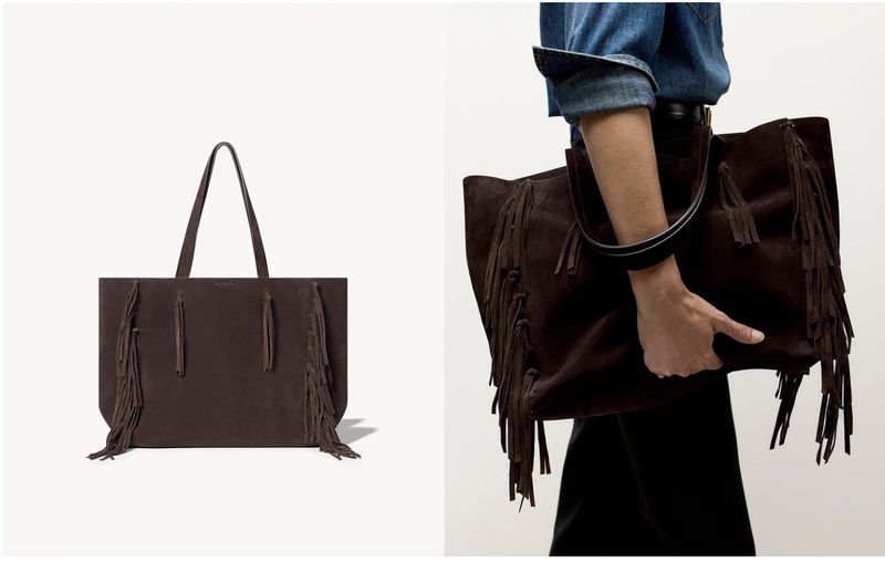 Brown suede tote bag with fringe detailing, held by a person in denim shirt and black pants, set against a white background.