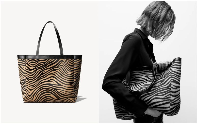 Fashionable tote bag with a zebra print design, black leather trim, and handles, shown in a studio with a woman holding the bag.