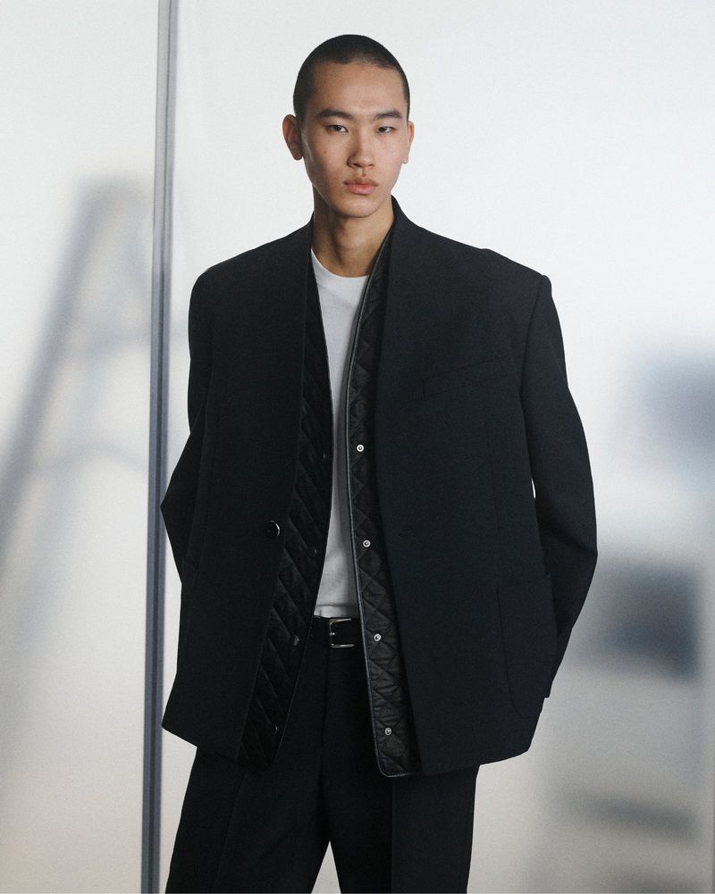 Model Yuto Ebihara posing in an oversized black blazer layered over a quilted black vest and white t-shirt against a light backdrop.