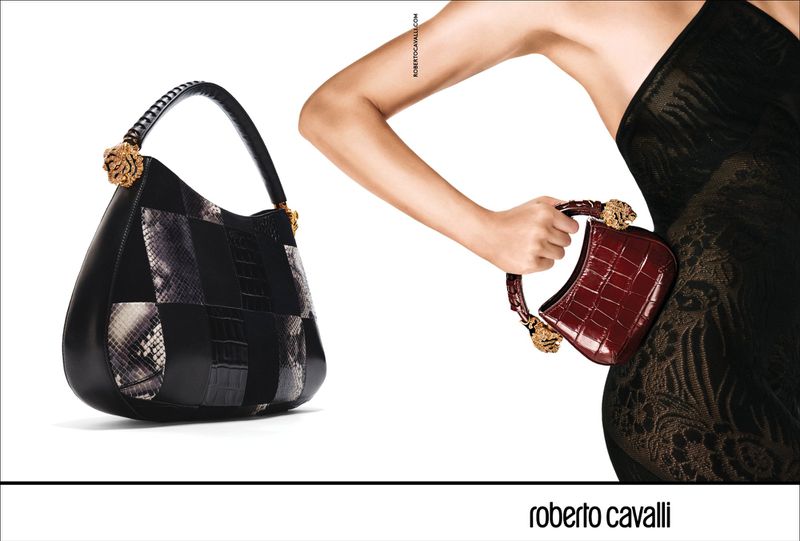 Fashion shot showcasing two Roberto Cavalli handbags: a patchwork hobo and a miniature crocodile bag held by a woman in a black dress.
