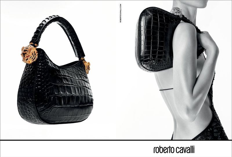 Fashion shot featuring a black crocodile-embossed handbag with golden tiger accents, carried by a model in a black and white setting.