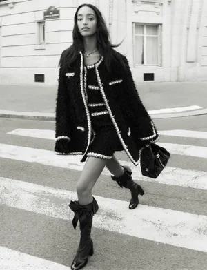 Mona Tougaard walking across a street in a Chanel tweed jacket and matching skirt, carrying a black handbag