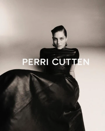 A striking black and white portrait of a stylish woman in a dark dress, exuding elegance and confidence against a muted backdrop.
