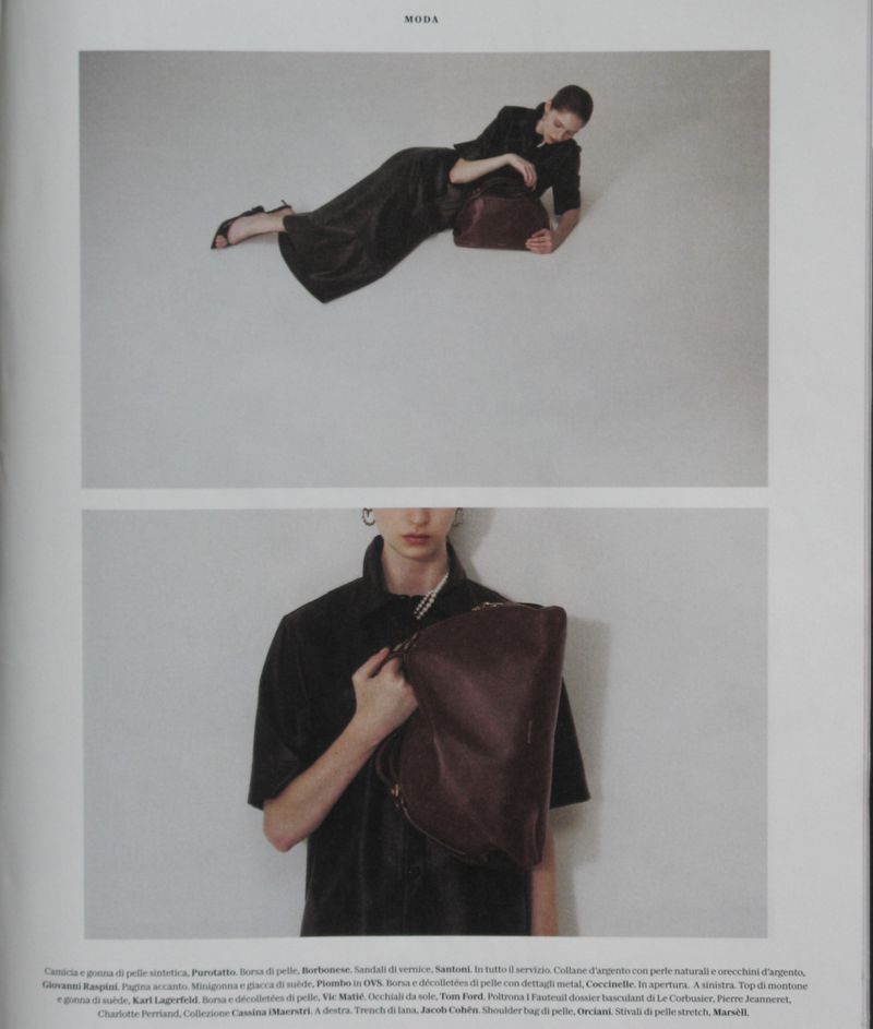 Editorial fashion shot of a model in a dark outfit lying down with a handbag in a studio setting; second shot of her holding a handbag.