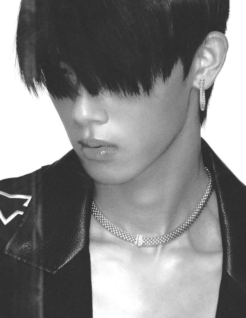Monochrome portrait of an adult male with dark hair wearing a black leather jacket and silver necklace and earring.