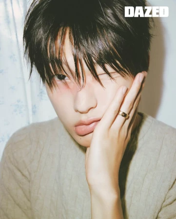 Close-up portrait of an Asian adult male model with dark hair and a sweater, touching his face and wearing a gold ring. Magazine cover.