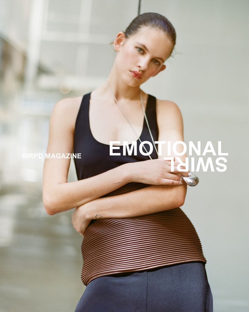 A woman models a black top and bronze skirt with modern styling against a neutral backdrop, featured in WRPO Magazine.