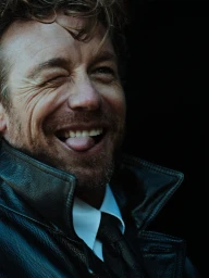 Close-up portrait of actor Simon Baker winking and sticking out tongue in a black leather jacket for Esquire Australia
