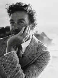 Portrait of Simon Baker in a patterned suit with hand to his chin for Esquire Australia.