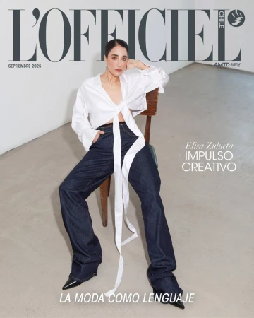 Magazine cover featuring a model wearing a white blouse and dark denim jeans, seated on a wooden chair against a neutral backdrop.