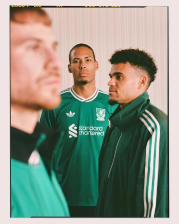 Three male soccer players in green vintage-style jerseys stand indoors for a sports-themed portrait; green, black, and white uniform details.