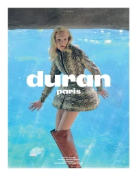 Model wearing a snakeskin print jacket and tall brown boots standing underwater in an aquarium by Juergen Teller for Duran Lantink.