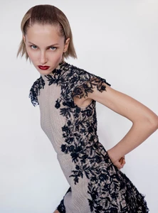 Model in a nude dress with black lace detailing posing against a plain white background for Vogue Hong Kong.