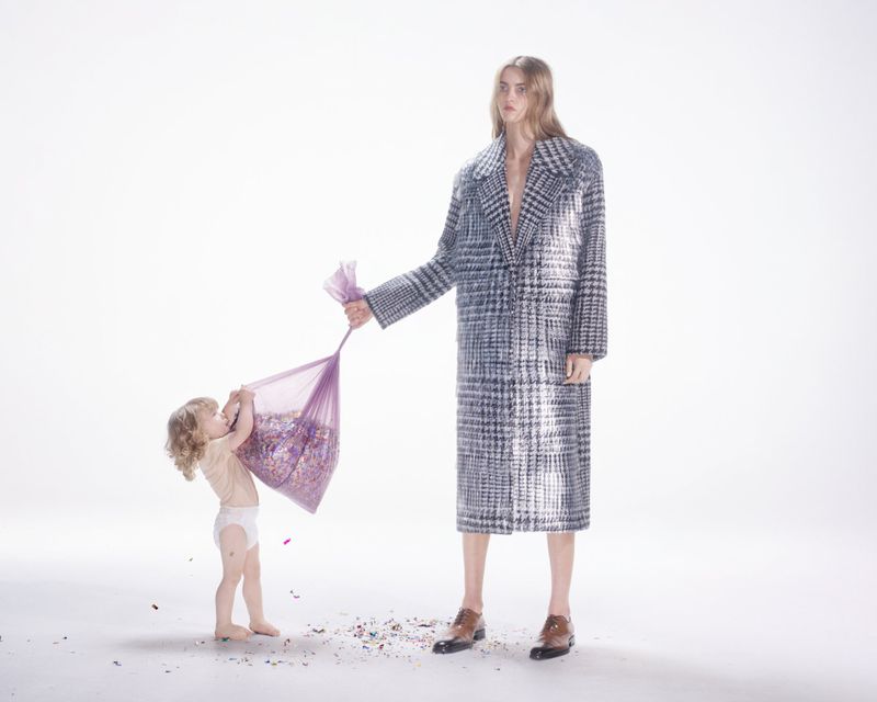 Fashion shot of an adult and child with a bag of colorful confetti in a bright studio, showcasing style and playful interaction.