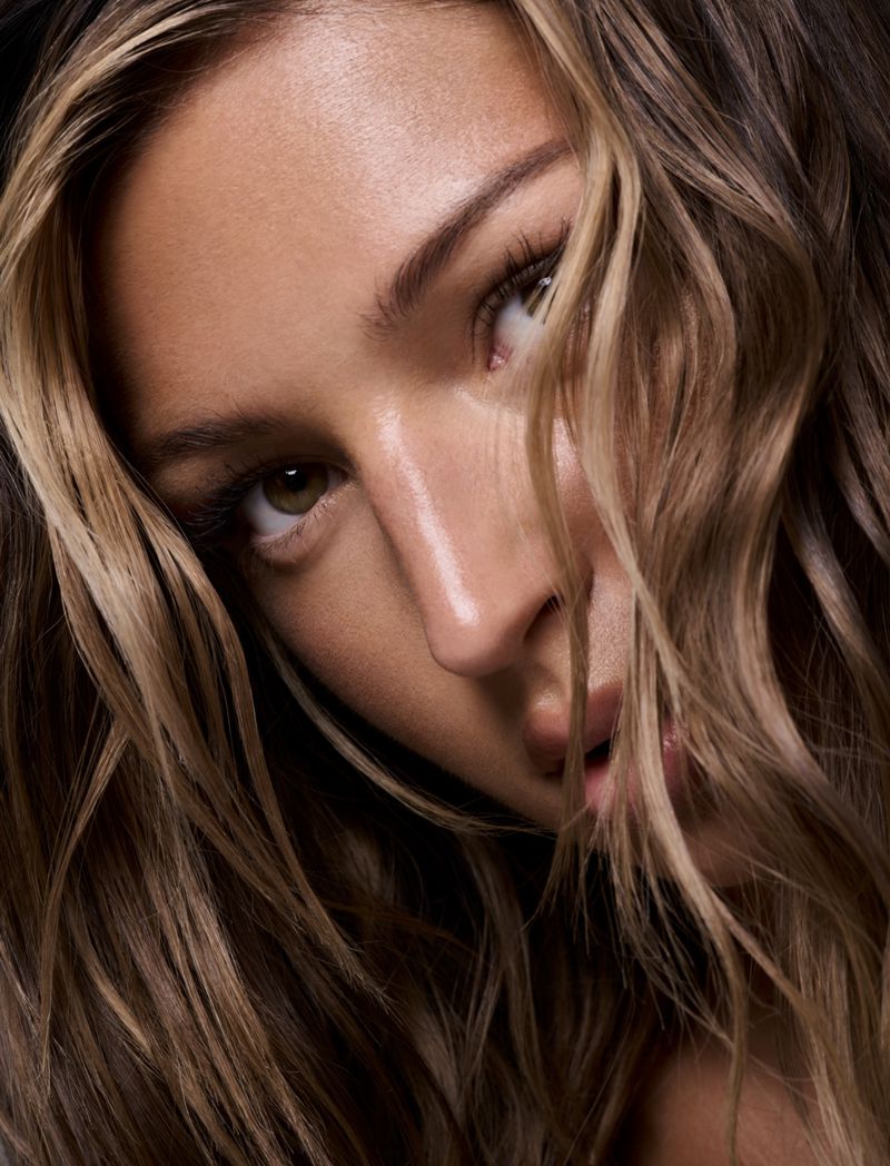 Close-up portrait of a woman with flowing blonde hair, showcasing beauty and style in a dark photo studio setting.