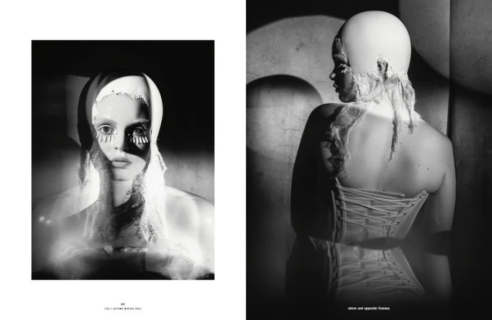 Monochrome studio shot features woman wearing white head covering and corset; bold eye makeup creates striking high fashion look.