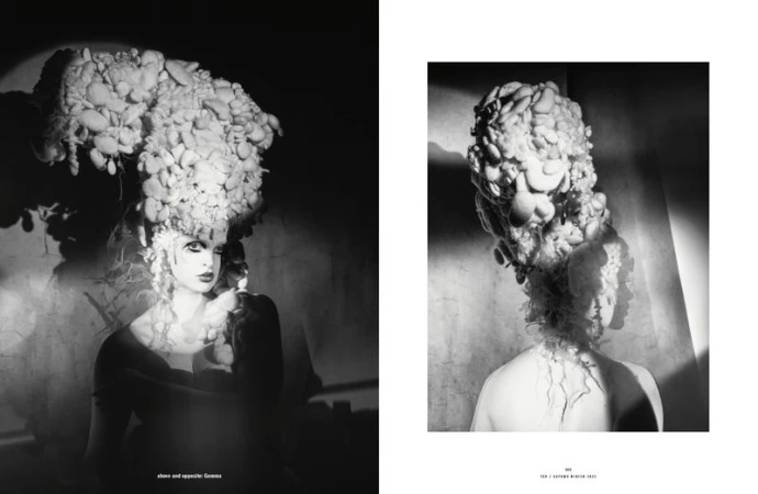Dramatic black-and-white fashion editorial featuring a woman with elaborate headwear and makeup in a studio setting with moody lighting.