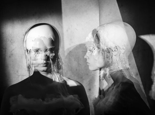 Monochrome portrait of two women with dramatic lighting and a surreal aesthetic, featuring lace details and artistic blurring.