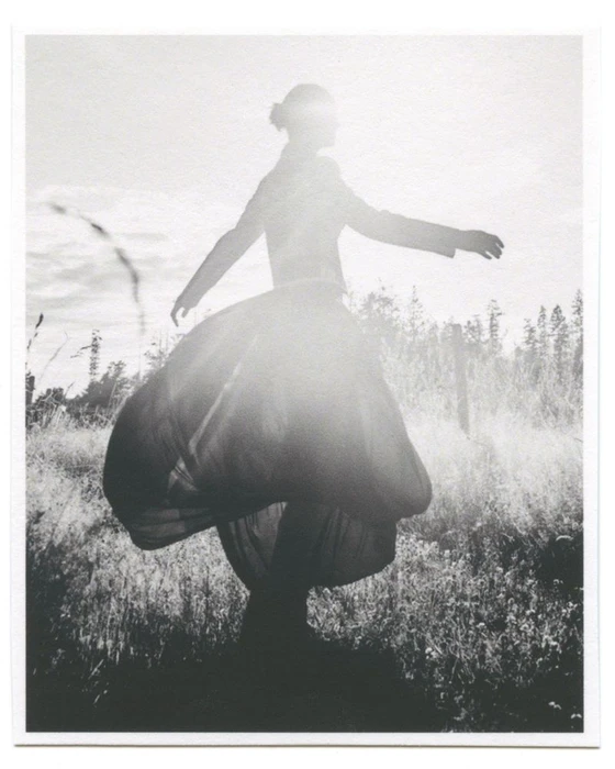 Tasha Tilberg in a voluminous balloon skirt spinning in a sunlit meadow for Clin d’œil Magazine.