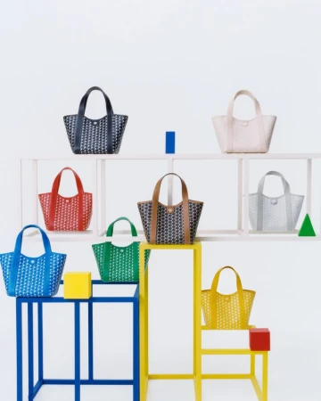 Colorful collection of patterned tote bags arranged on geometric white and colored display platforms against a white backdrop.