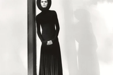 Model in black turtleneck dress and round headpiece standing against a pillar for W Magazine Natural Selection editorial
