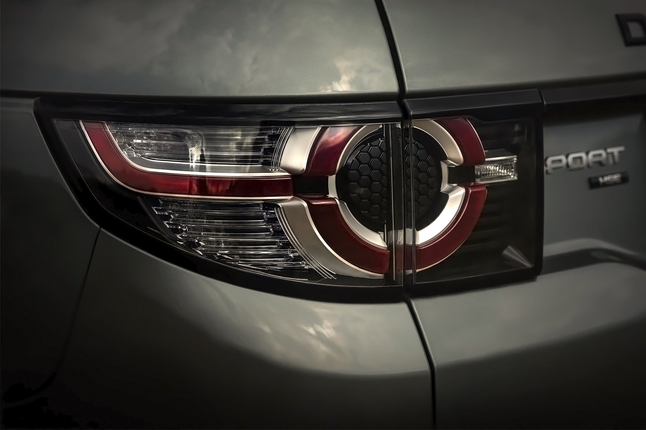 Close-up of a gray Land Rover Discovery Sport taillight with a silver and red design, showcasing automotive design elements.
